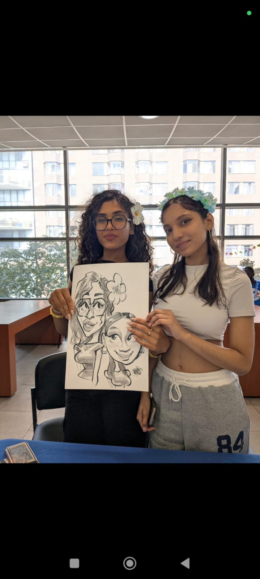 Two students holding a black and white caricature drawn live by Juan