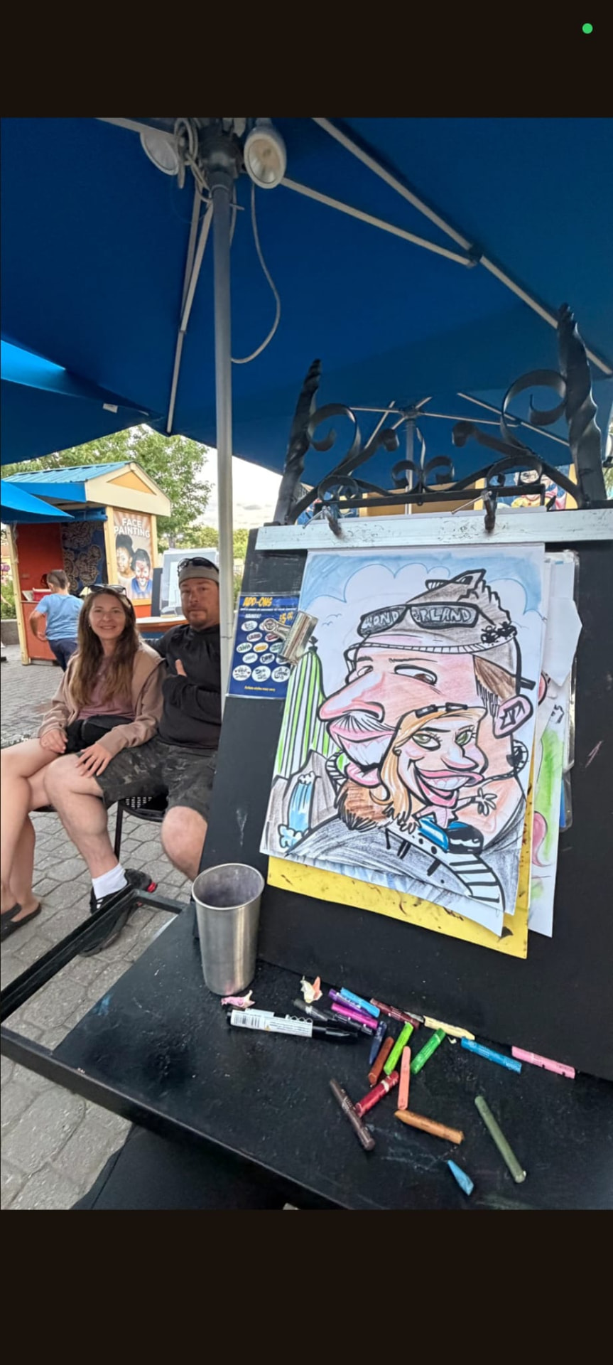 Couple seated with their colour caricature on the easel