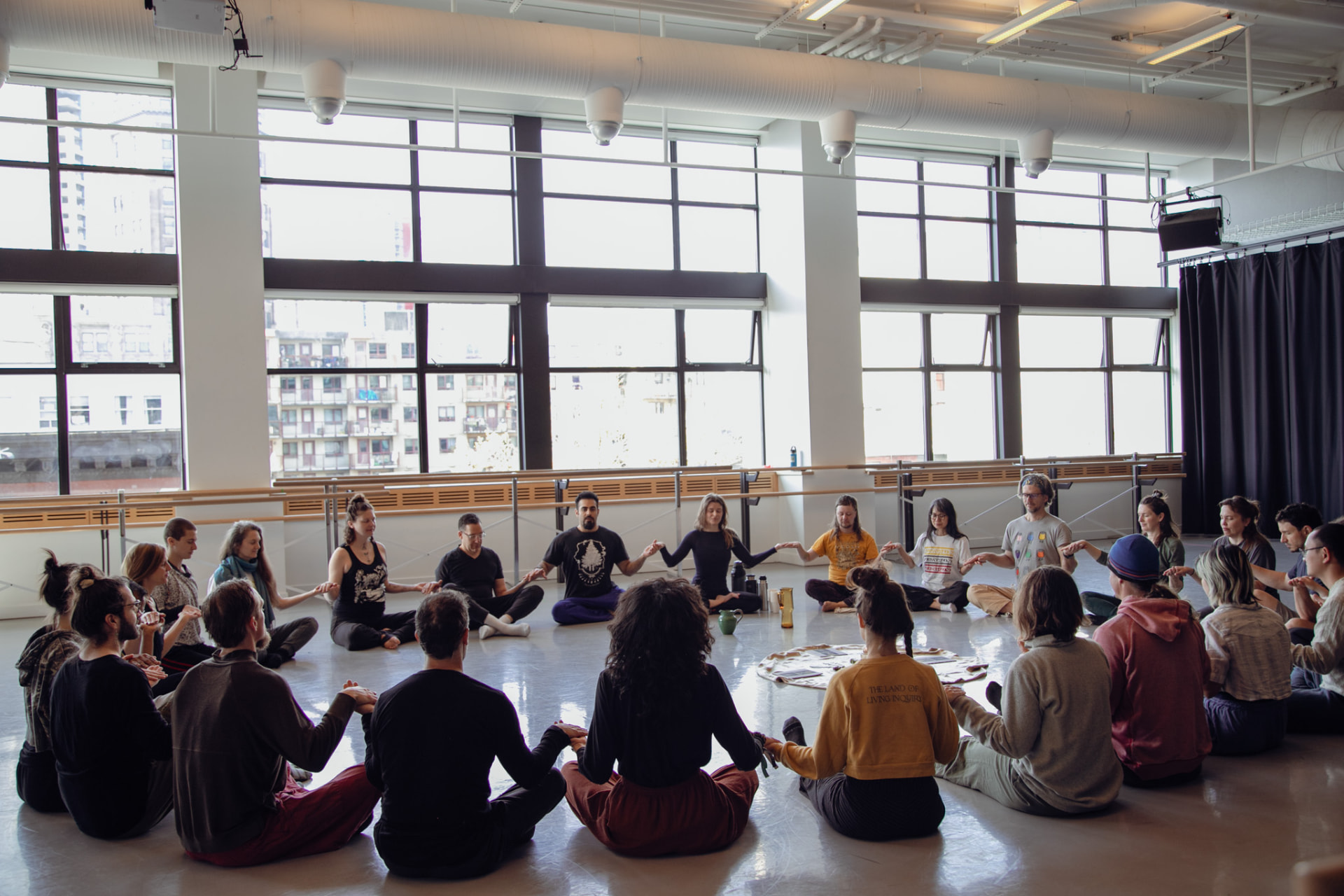 Opening circle — hands held in the glass studio